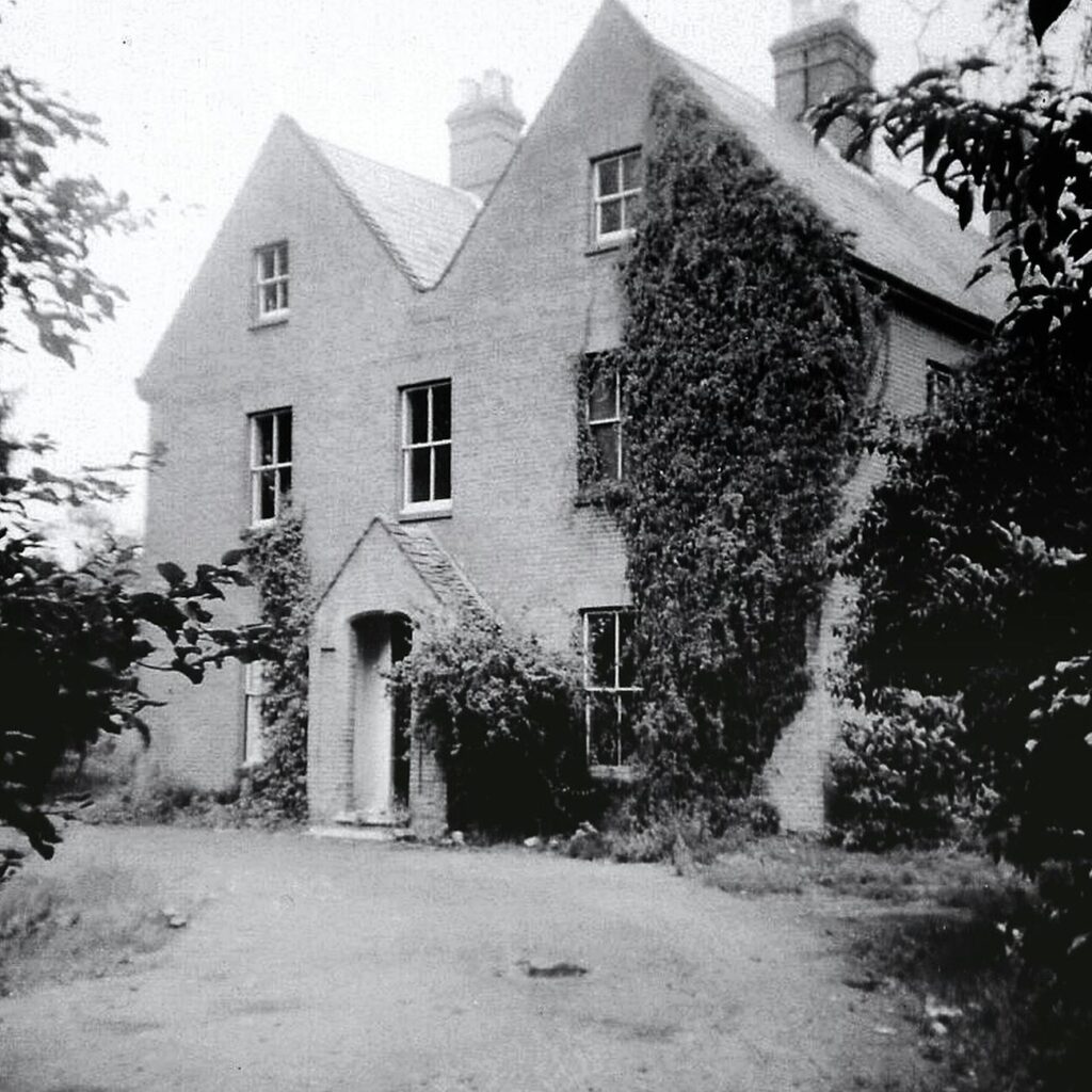 grayscale photo of concrete house along an unpaved pathway