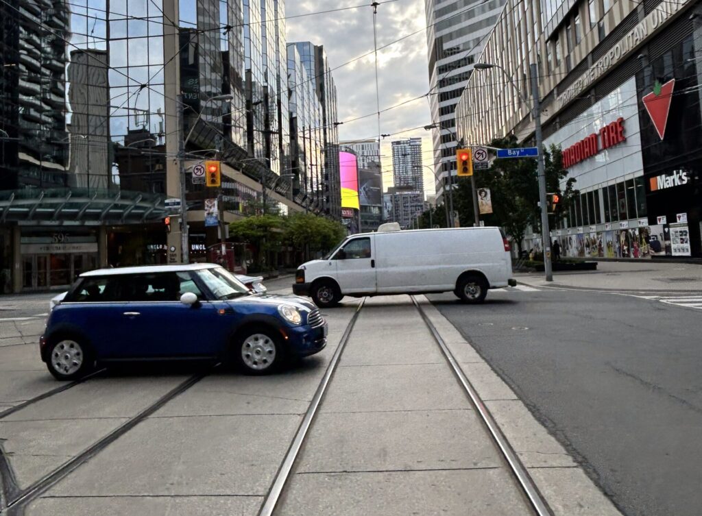 Downtown Toronto Road with two cars going through an intersection.